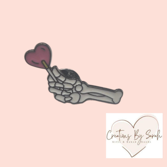 skeleton hand, with heart lolly pin badge